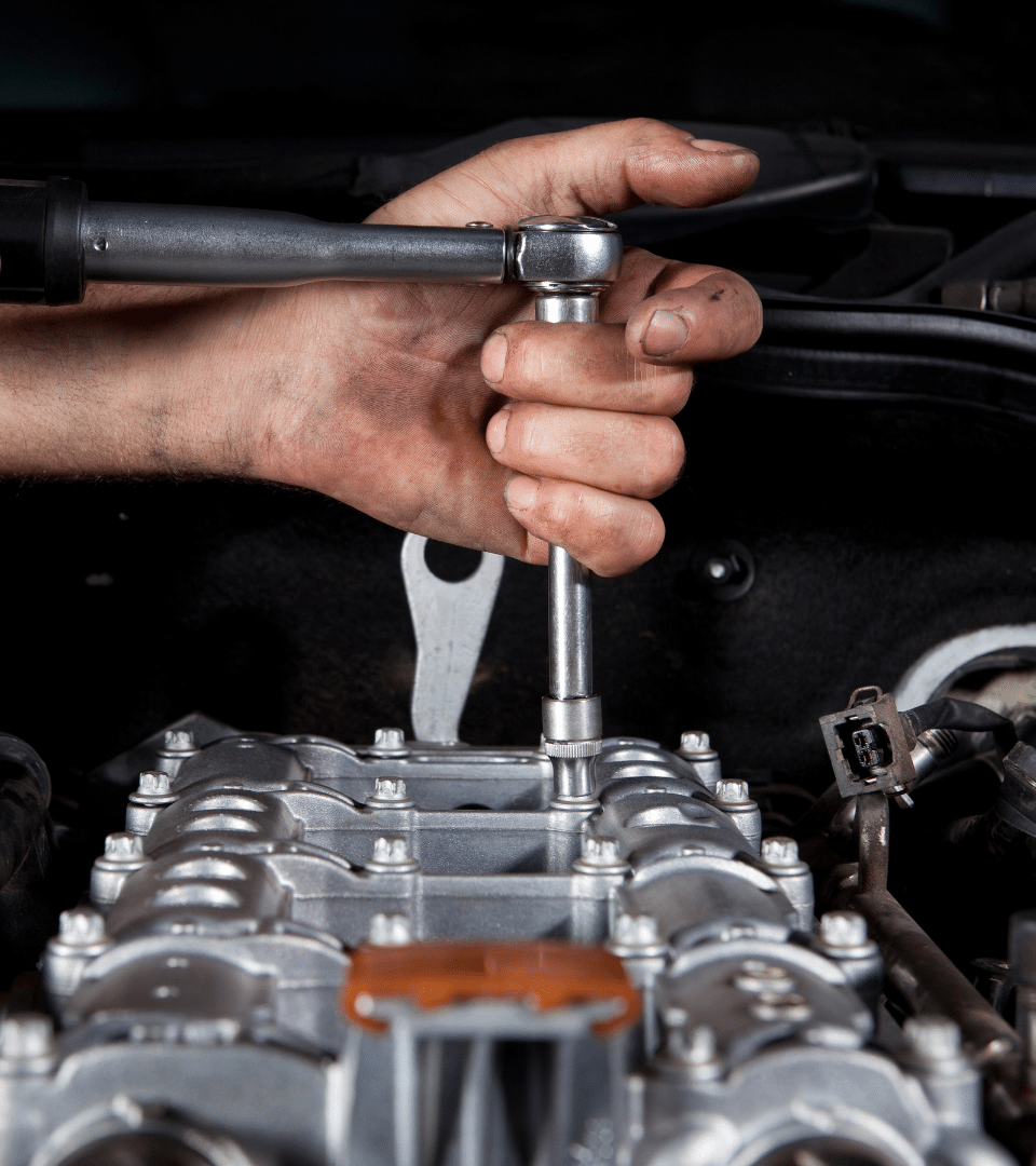 mao de homem , mecanico a apertar com uma chave a cabeça de motor de uma viatura