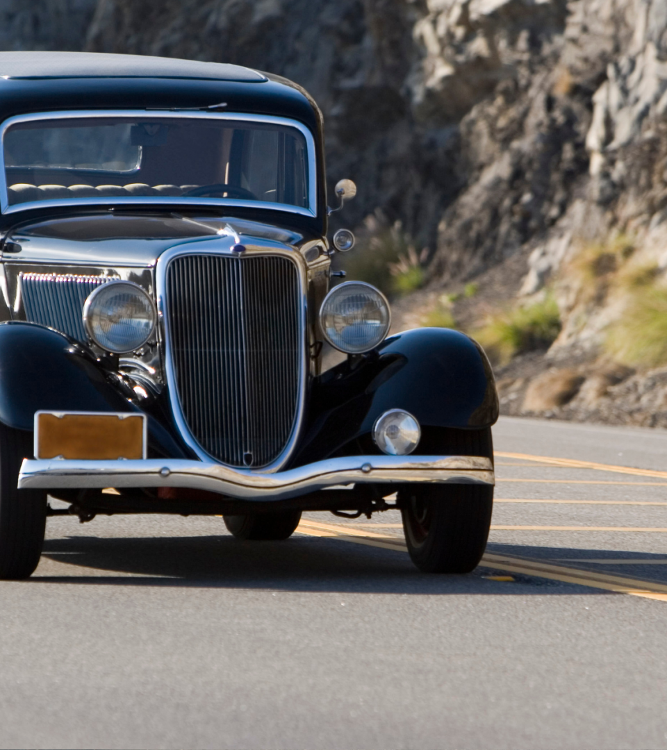 Uma imagem de um carro clássico evoca uma sensação nostálgica e atemporal. Visualize um veículo elegantemente desenhado, com curvas suaves e linhas aerodinâmicas que capturam a essência do design automotivo de eras passadas. A pintura reluzente, muitas vezes em tons profundos e ricos, realça a beleza intemporal do veículo.